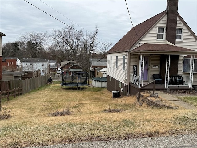 view of property exterior with a trampoline, a lawn, and a porch