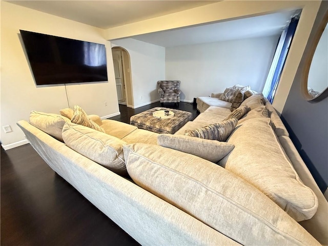 living room featuring beamed ceiling and dark hardwood / wood-style flooring