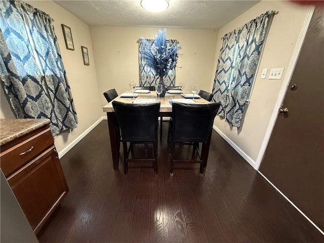 dining space featuring dark wood-type flooring and a textured ceiling