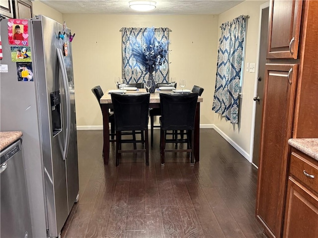 dining area with a textured ceiling and dark hardwood / wood-style flooring