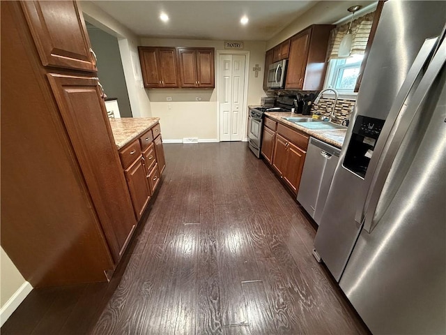 kitchen with sink, hanging light fixtures, stainless steel appliances, dark hardwood / wood-style flooring, and decorative backsplash