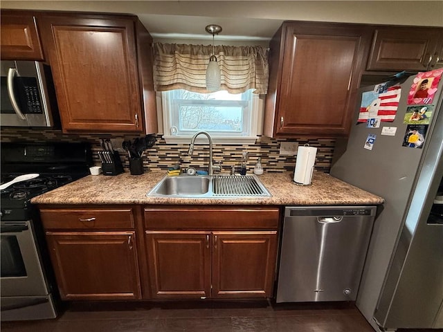 kitchen featuring stainless steel appliances, tasteful backsplash, sink, and decorative light fixtures