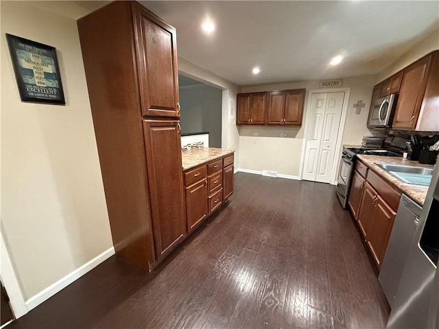 kitchen featuring light stone countertops, appliances with stainless steel finishes, sink, and dark hardwood / wood-style flooring