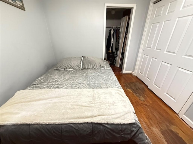 bedroom with dark wood-type flooring and a closet