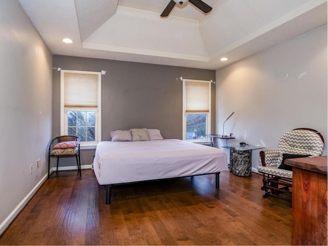 bedroom featuring dark wood-type flooring, a raised ceiling, and ceiling fan