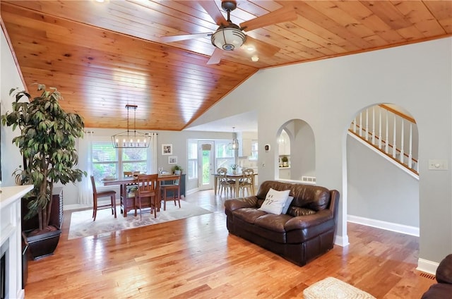 living room with vaulted ceiling, ceiling fan with notable chandelier, wooden ceiling, and light hardwood / wood-style flooring