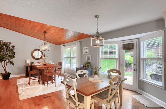 dining space with a textured ceiling, vaulted ceiling, light hardwood / wood-style floors, and wooden ceiling