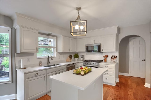 kitchen with pendant lighting, sink, appliances with stainless steel finishes, white cabinets, and a kitchen island