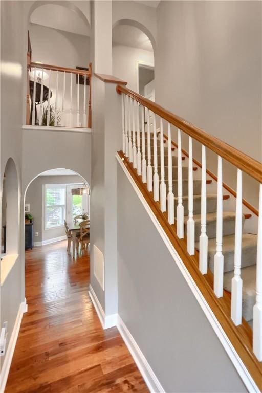 staircase with a towering ceiling and wood-type flooring