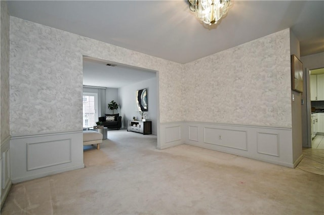 carpeted spare room featuring an inviting chandelier