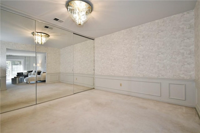 carpeted spare room featuring a notable chandelier