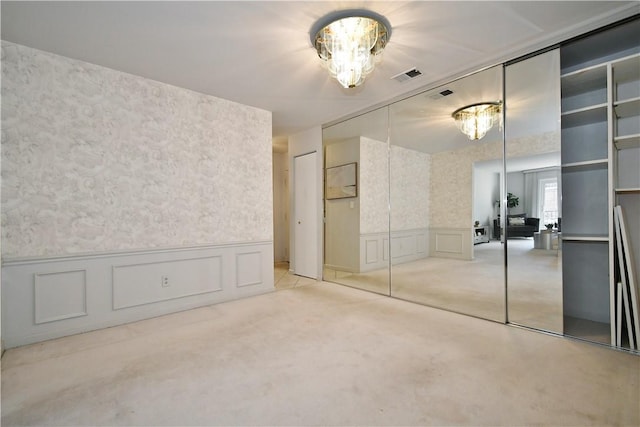 unfurnished bedroom featuring a notable chandelier and light colored carpet