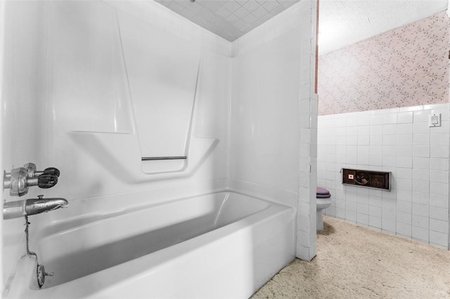 bathroom featuring tile walls, shower / washtub combination, and toilet