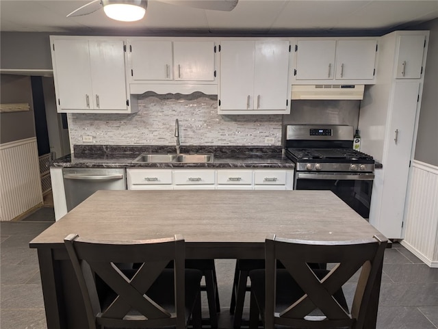 kitchen with sink, backsplash, stainless steel appliances, white cabinets, and dark tile patterned flooring