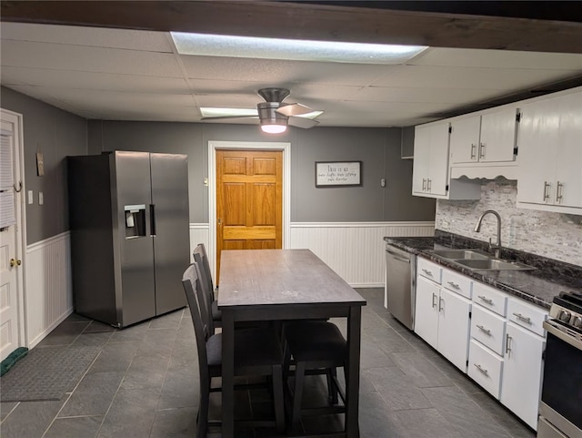 kitchen with white cabinetry, sink, dark stone countertops, ceiling fan, and stainless steel appliances