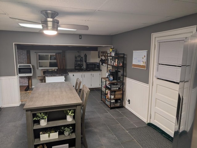 kitchen with a paneled ceiling, heating unit, white cabinets, and ceiling fan