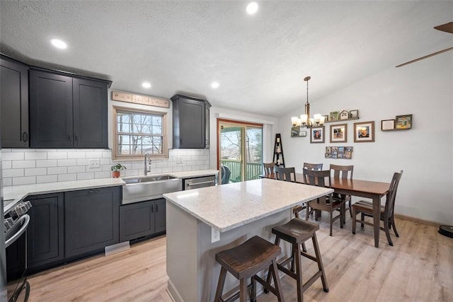 kitchen featuring a kitchen island, decorative light fixtures, sink, a kitchen bar, and electric stove