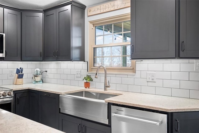 kitchen featuring light stone counters, sink, decorative backsplash, and appliances with stainless steel finishes