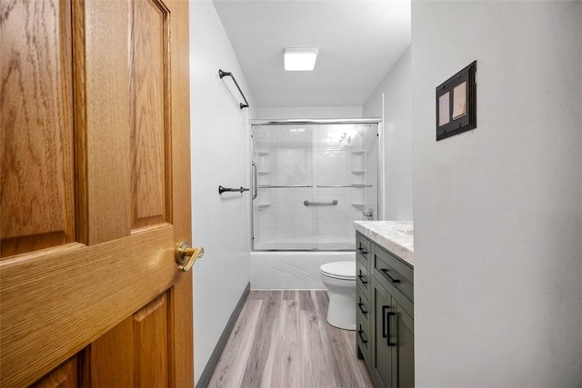 full bathroom featuring vanity, toilet, combined bath / shower with glass door, and hardwood / wood-style floors