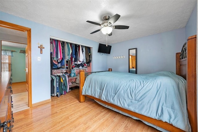 bedroom featuring ceiling fan, a textured ceiling, light wood-type flooring, and a closet