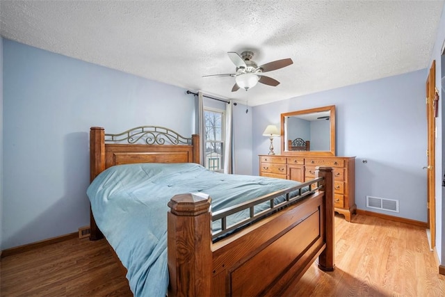 bedroom with wood-type flooring, ceiling fan, and a textured ceiling