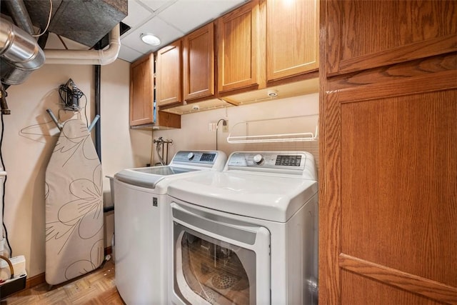 clothes washing area with cabinets, light parquet floors, and washing machine and clothes dryer