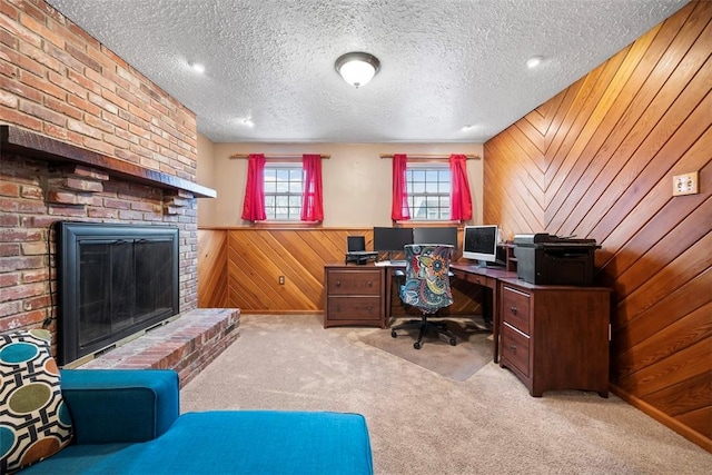 office space featuring light carpet, a brick fireplace, wooden walls, and a textured ceiling