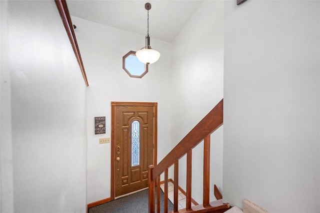 entrance foyer with a towering ceiling and dark colored carpet