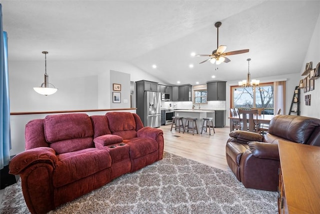 living room with vaulted ceiling, sink, ceiling fan with notable chandelier, and light hardwood / wood-style flooring