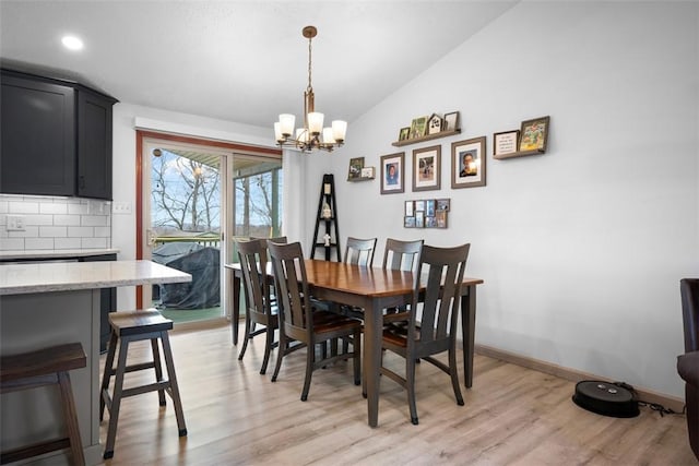 dining room featuring lofted ceiling, an inviting chandelier, and light hardwood / wood-style floors