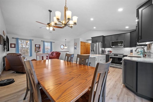 dining room featuring lofted ceiling, sink, ceiling fan with notable chandelier, and light wood-type flooring