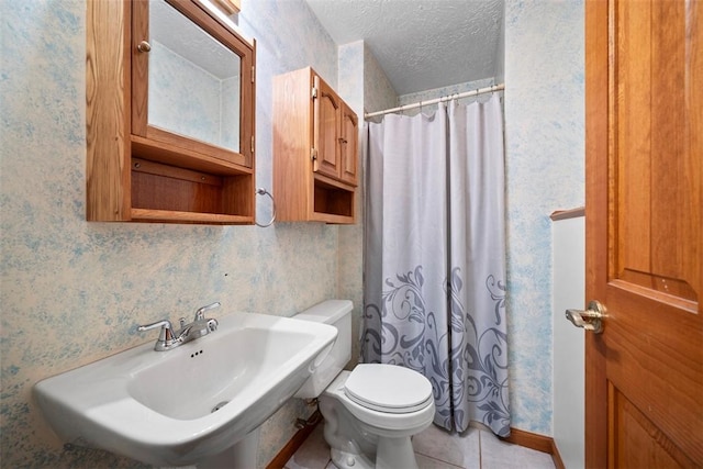 bathroom with walk in shower, toilet, sink, a textured ceiling, and tile patterned flooring