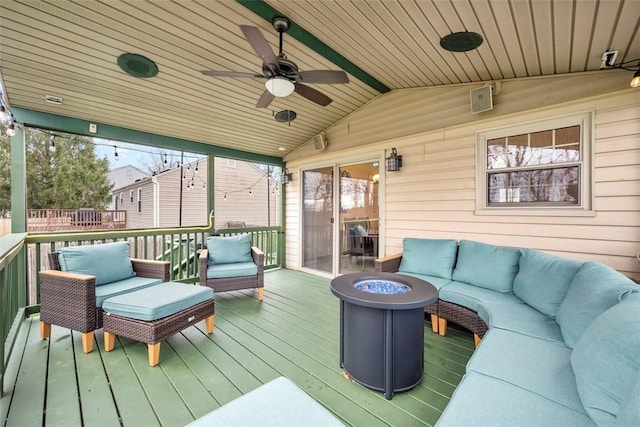 wooden terrace featuring ceiling fan and an outdoor living space with a fire pit