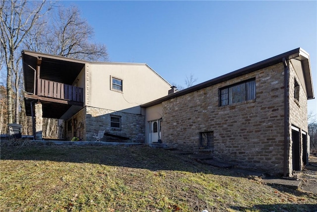 view of side of property with a balcony, a yard, and a garage