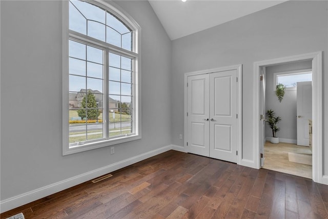 unfurnished room featuring vaulted ceiling and dark hardwood / wood-style floors