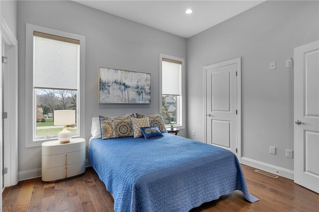 bedroom with dark hardwood / wood-style floors and multiple windows