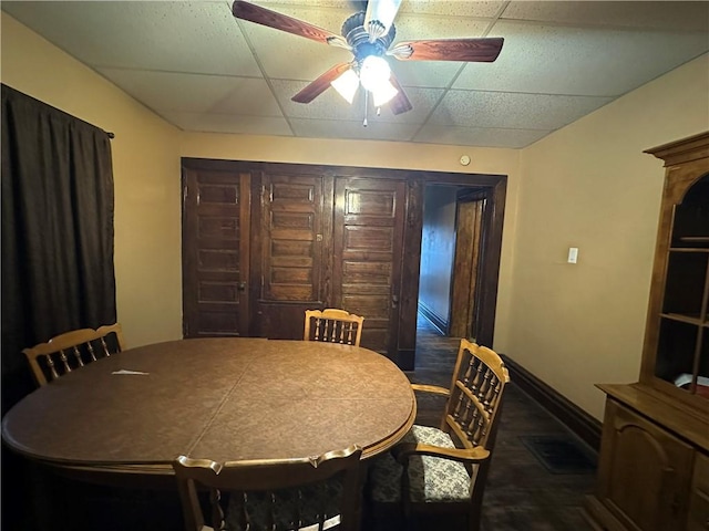 dining space with a drop ceiling and ceiling fan