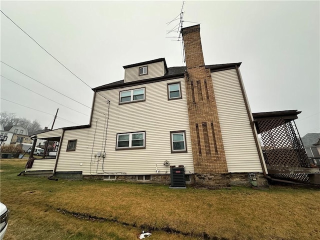 back of property with central AC and a lawn