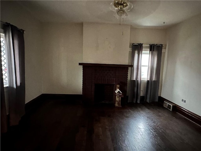 unfurnished living room with a brick fireplace and dark hardwood / wood-style floors