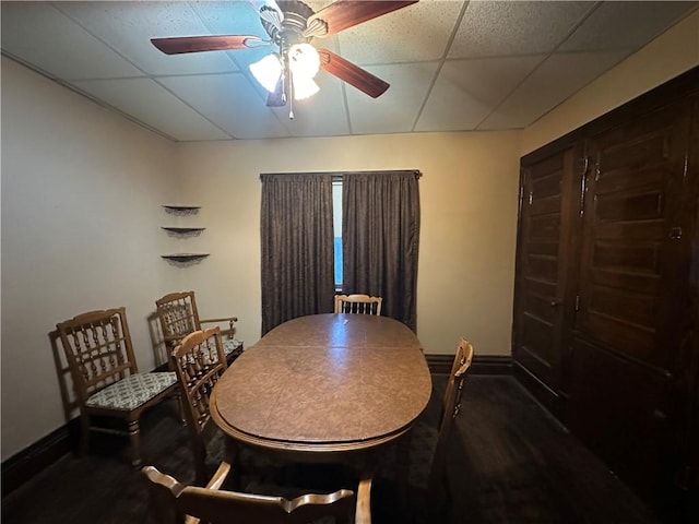 dining room with dark hardwood / wood-style floors, a drop ceiling, and ceiling fan