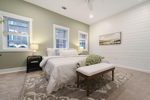 bedroom with ceiling fan, light colored carpet, and wood walls