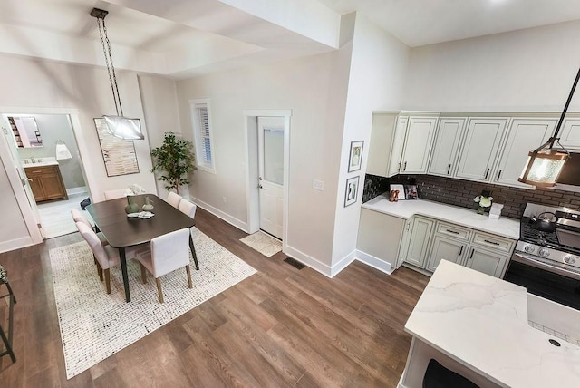 kitchen with pendant lighting, dark hardwood / wood-style flooring, light stone countertops, and tasteful backsplash