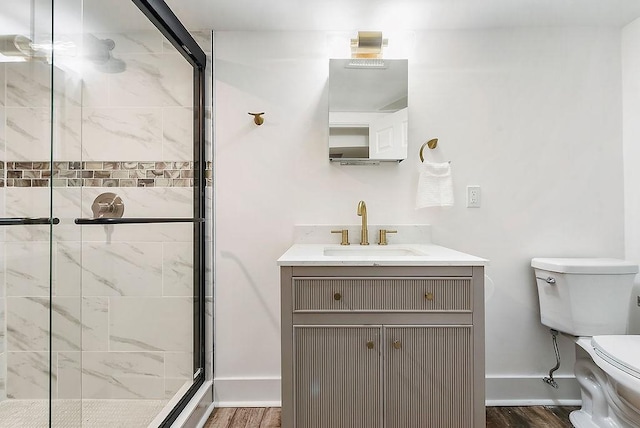 bathroom featuring vanity, toilet, a shower with door, and wood-type flooring