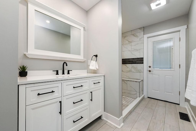 bathroom with a tile shower, vanity, and hardwood / wood-style floors