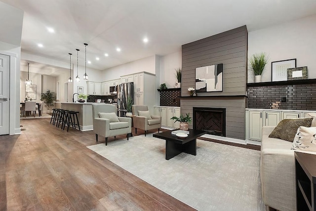 living room with a large fireplace, sink, and light wood-type flooring