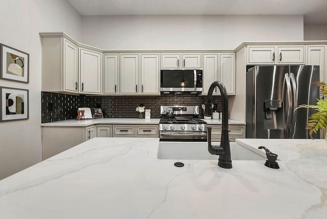 kitchen with tasteful backsplash, appliances with stainless steel finishes, and light stone counters