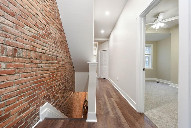 hallway featuring brick wall and dark hardwood / wood-style flooring