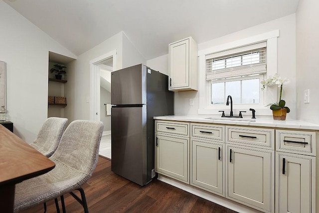 kitchen with lofted ceiling, sink, dark wood-type flooring, and stainless steel refrigerator