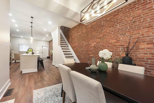 dining space with brick wall, wood-type flooring, and sink