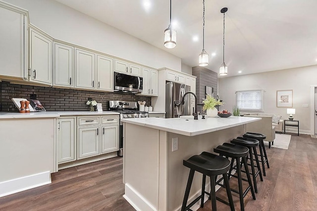 kitchen featuring pendant lighting, stainless steel appliances, dark hardwood / wood-style floors, a center island with sink, and decorative backsplash